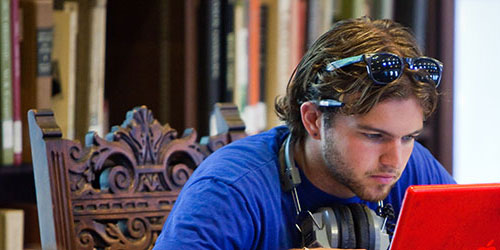 A student studying on a laptop in the library.