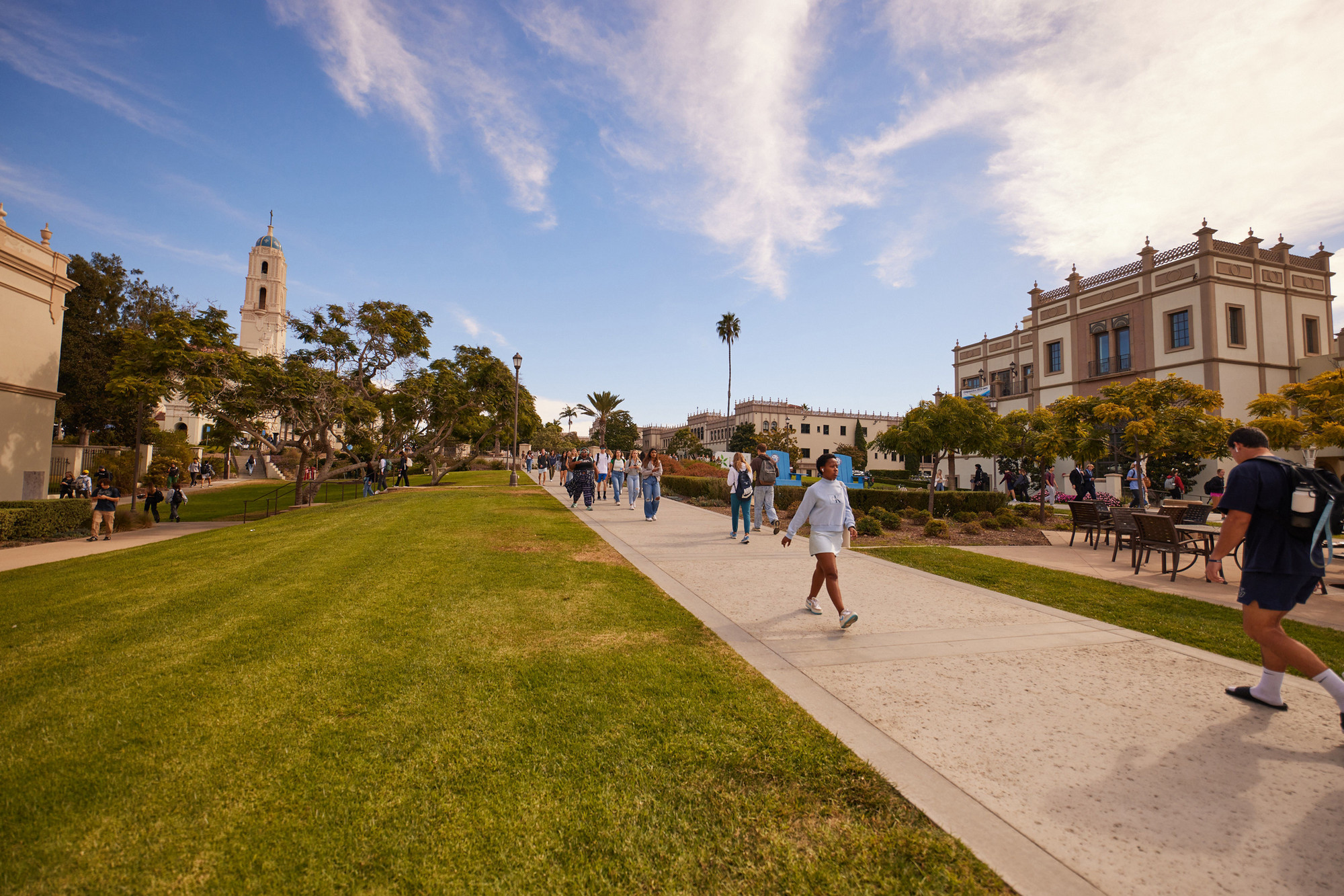 students walking on campus with blue skies
