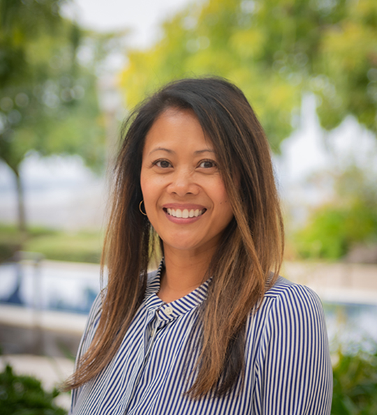 Headshot of woman with tan skin and brown hair wearing a blue and white striped shirt