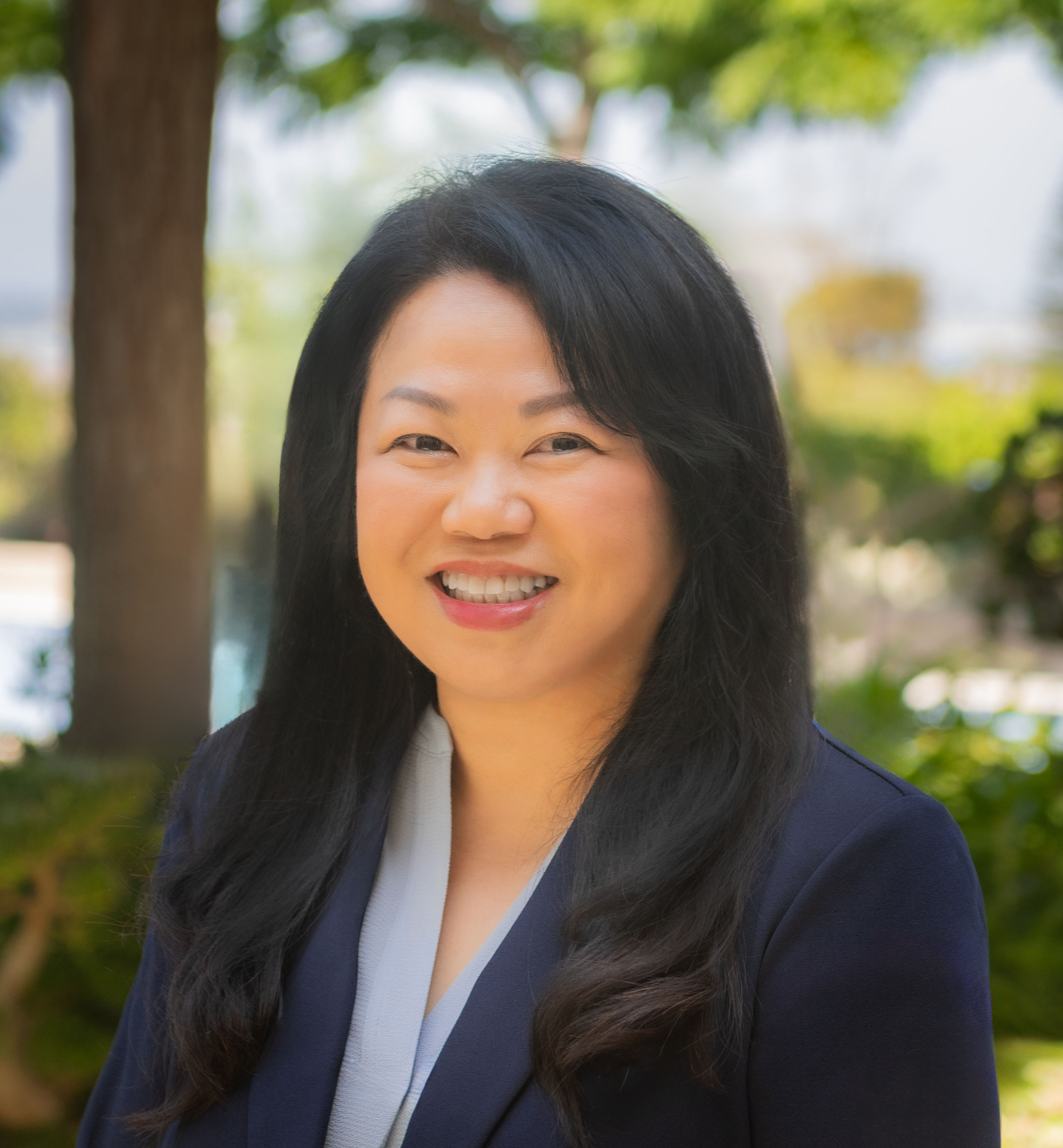 Headshot of woman with black hair wearing a light blue shirt and dark navy blazer