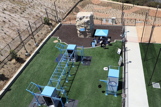 Exterior aerial shot of turn field with blue gym equipment and outdoor climbing wall