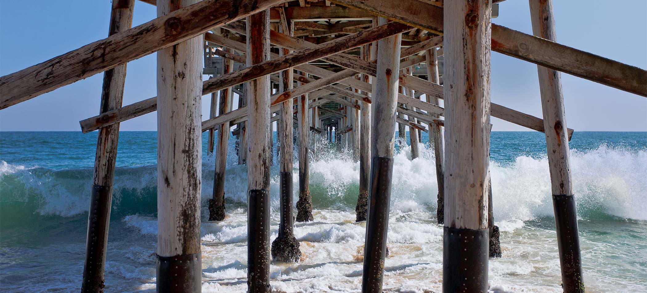 a pier in orange county with waves splashing