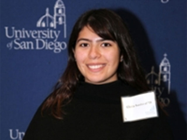 Female student smiling in front of blue backdrop