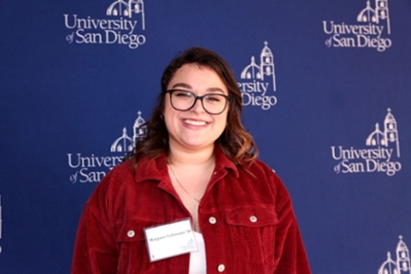 Female student smiling in front of blue backdrop