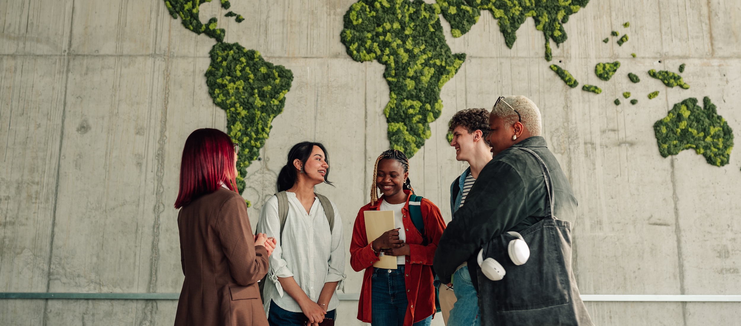students in front of a wall with greenery in the shape of a map