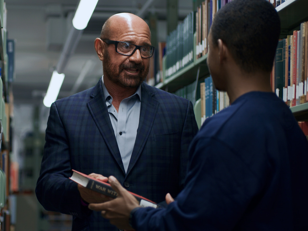 Professor speaking with student in the library