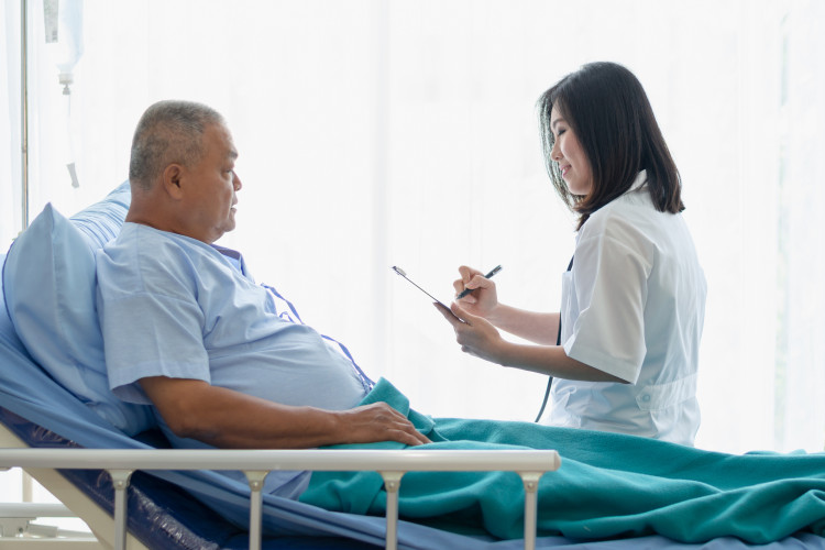 An Asian doctor visits with an elderly Asian patient in a hospital room