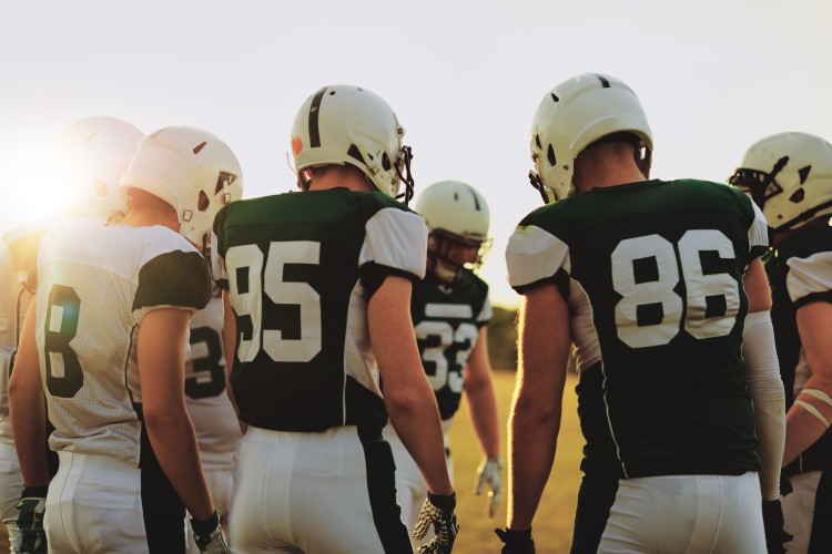 A football team stands in a huddle
