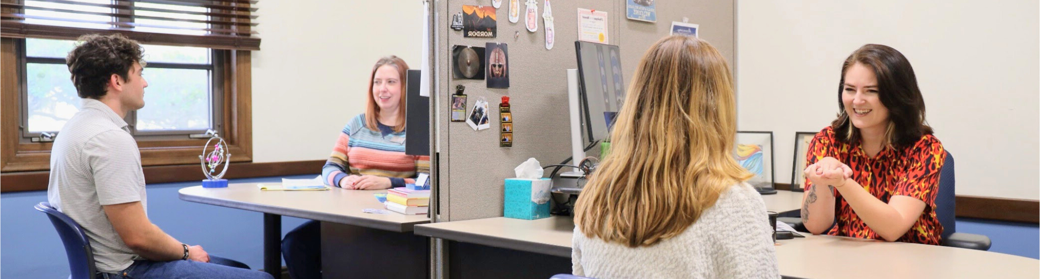 Advisors Emily Bolender and Karina Westra in their office talking with two students