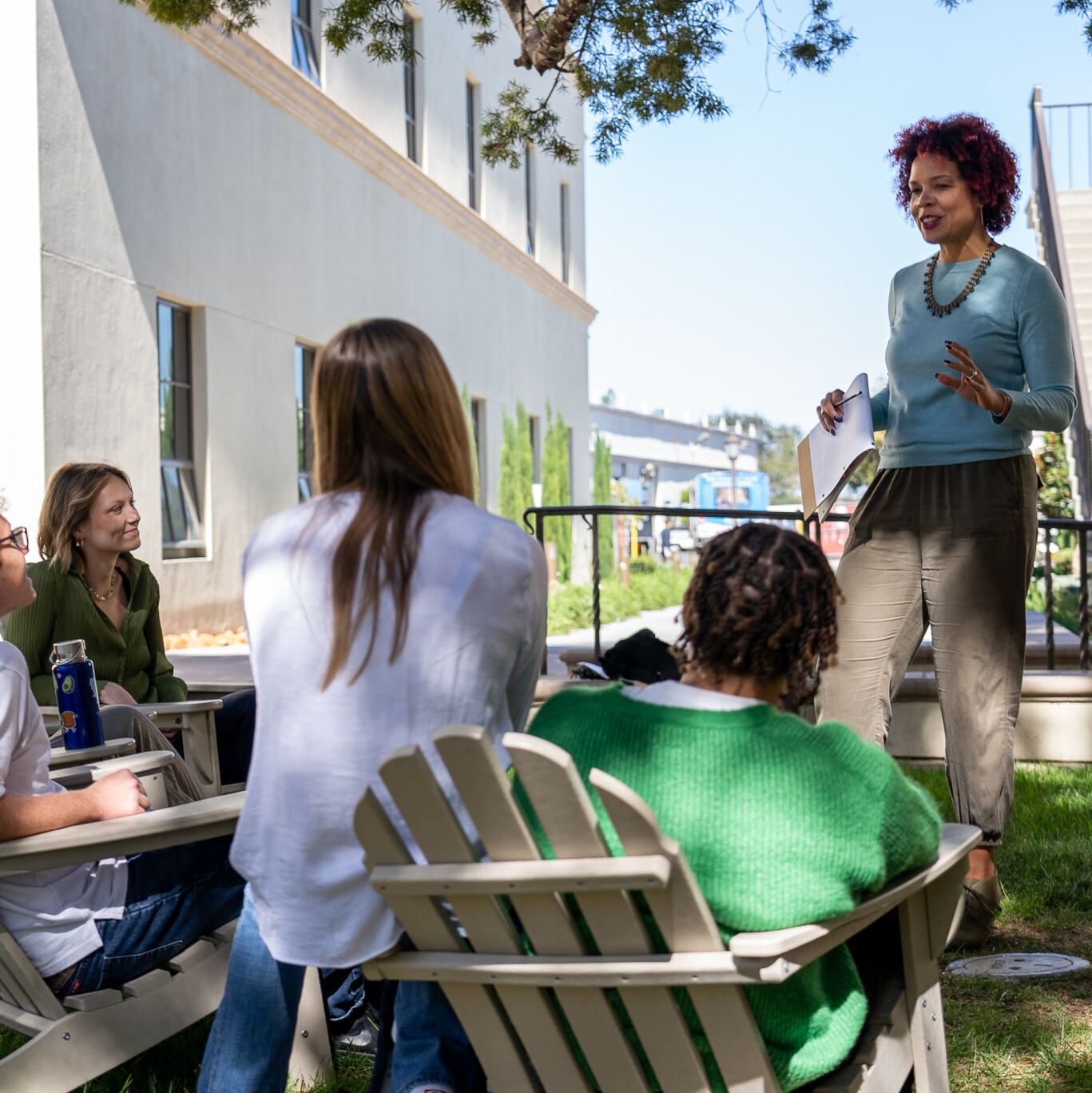 Professor Jillian Tullis leading a small group discussion with students outside on the lawn.