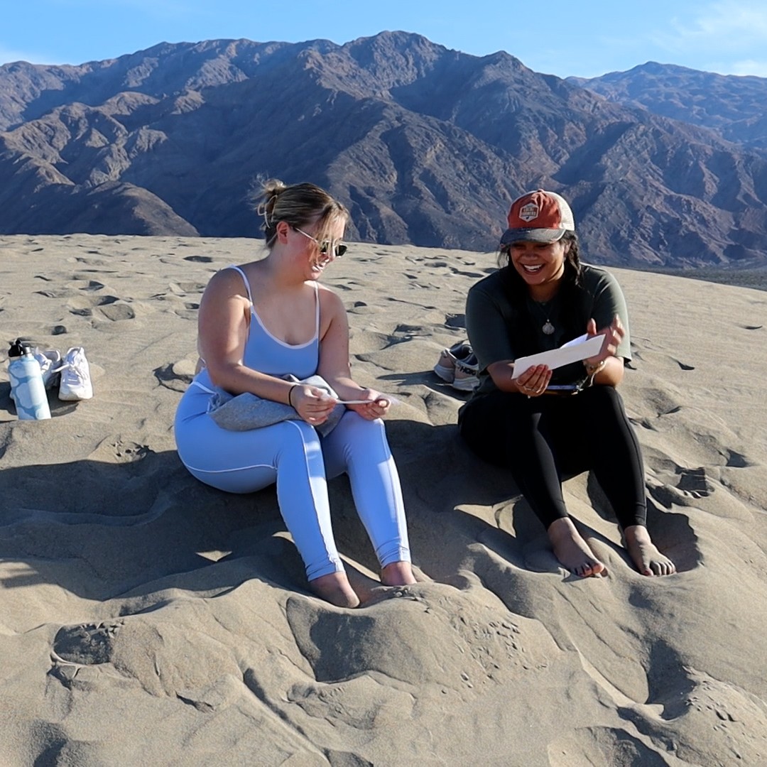 Two students out in the desert discussing a text as part of a class trip.