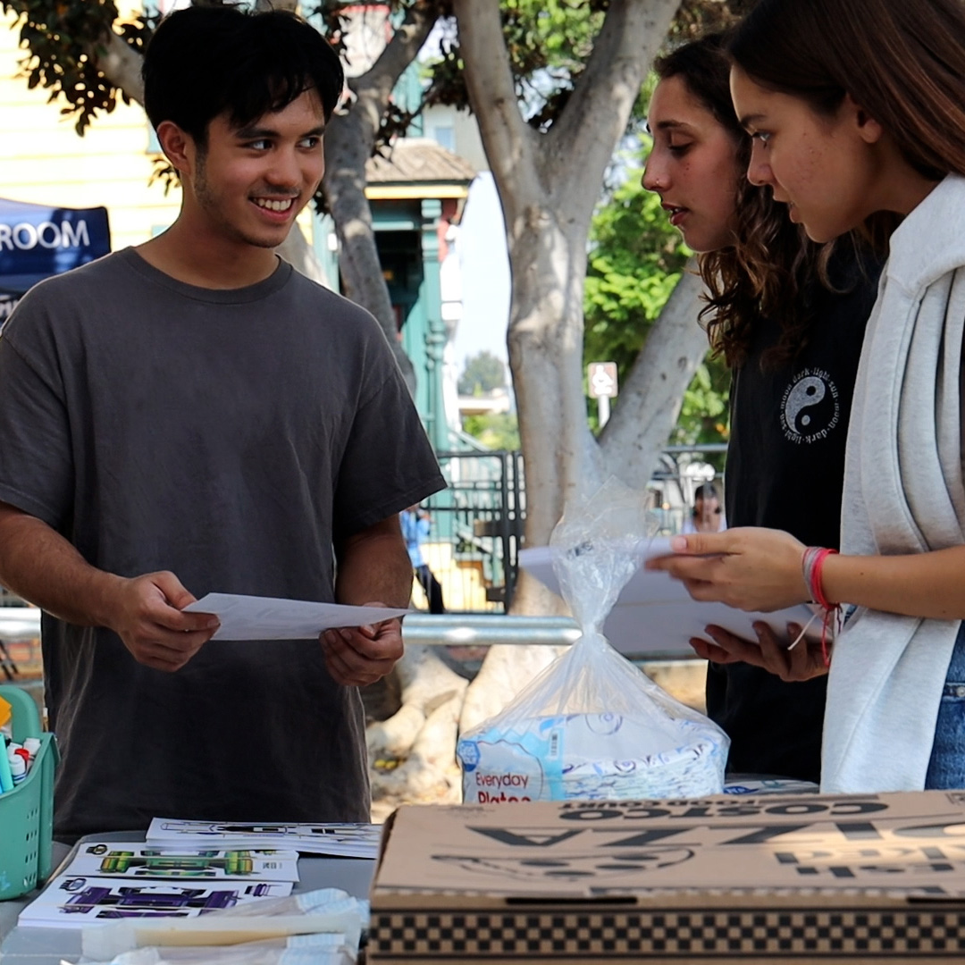Three students preparing for the Turning Wheel Mobile Classroom event.