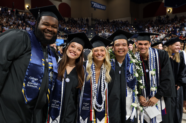 Students smiling at graduation ceremony.