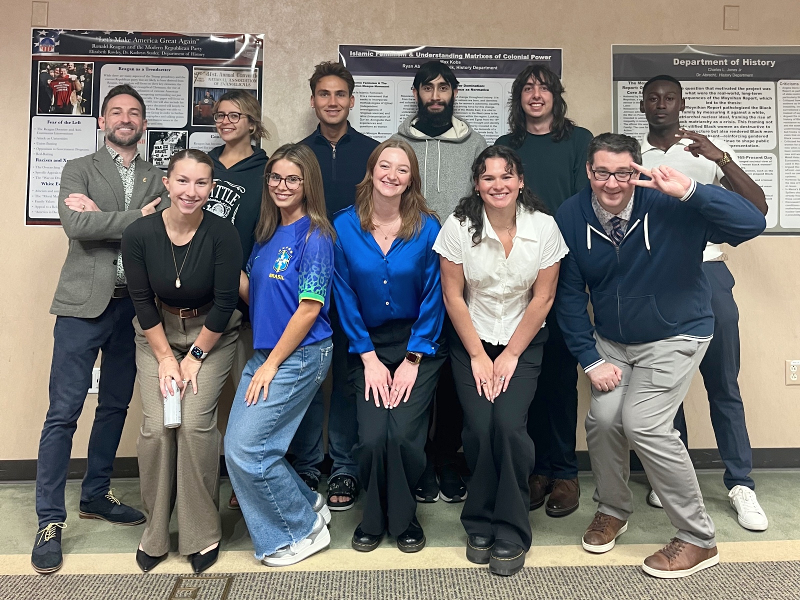 A group of students standing in front of their research posters with their professor.