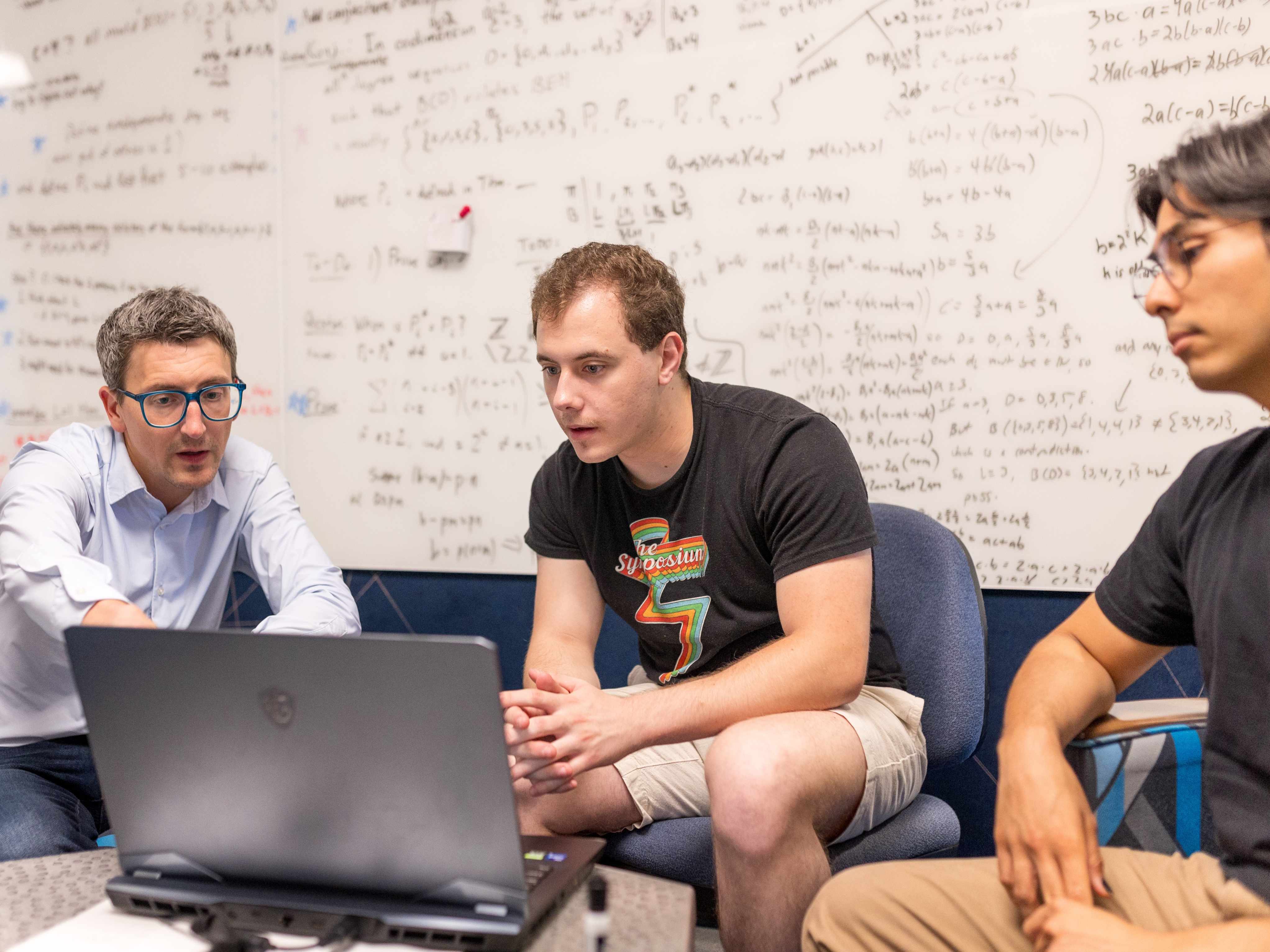Two students with Associate Professor Adam Boocher working on a research project.