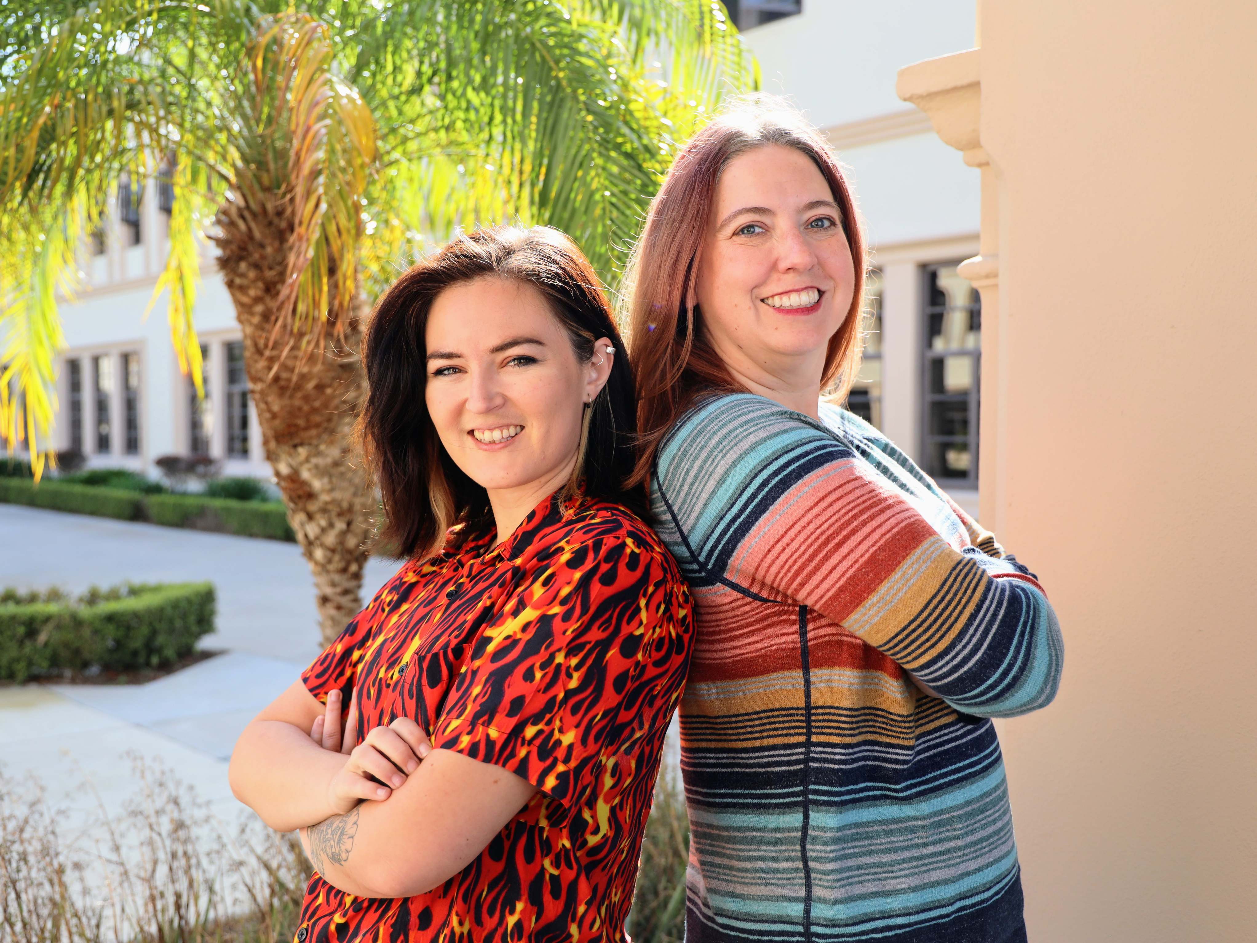 Advisors Emily Bolender and Karina Westra standing back to back in Founders courtyard