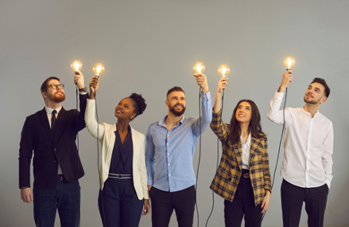 A group of people each holding up a lighted lightbulb