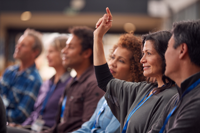 A person in a group of people raises their hand.