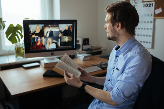 A person sits at a computer meeting with other folks virtually.