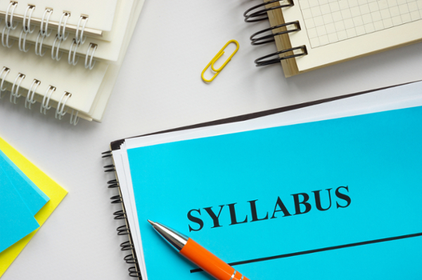 A blank syllabus with pens and additional materials surrounding.