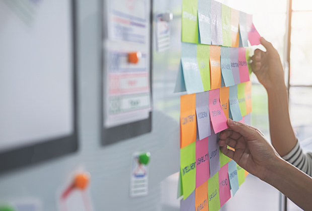 decorative image of people taking off post-it notes on a board with various resources