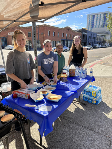 USD Students standing at a table in downtown San Diego, serving pancakes