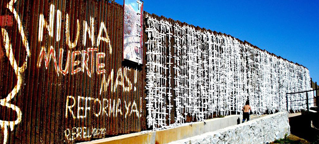 U.S. Mexico border wall with graffiti reading "Niuna muerte mas! Reforma ya!"