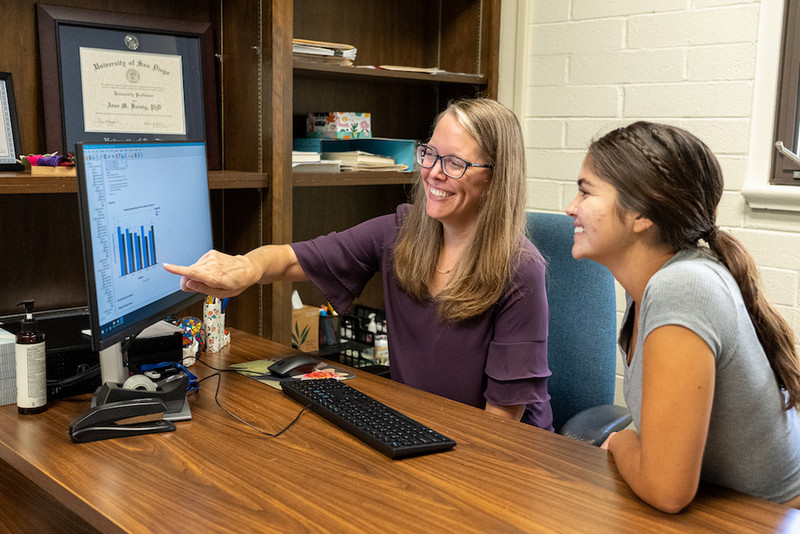 Anne Koenig pointing at the computer with a student