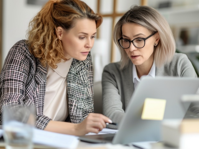 Two women working on a laptop collaboratively