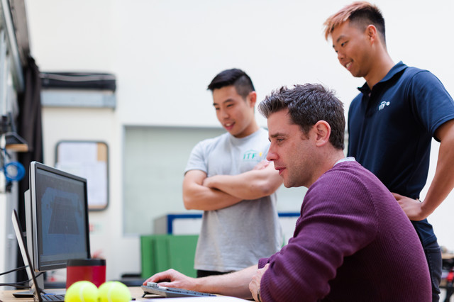 Three male students working on a laptop