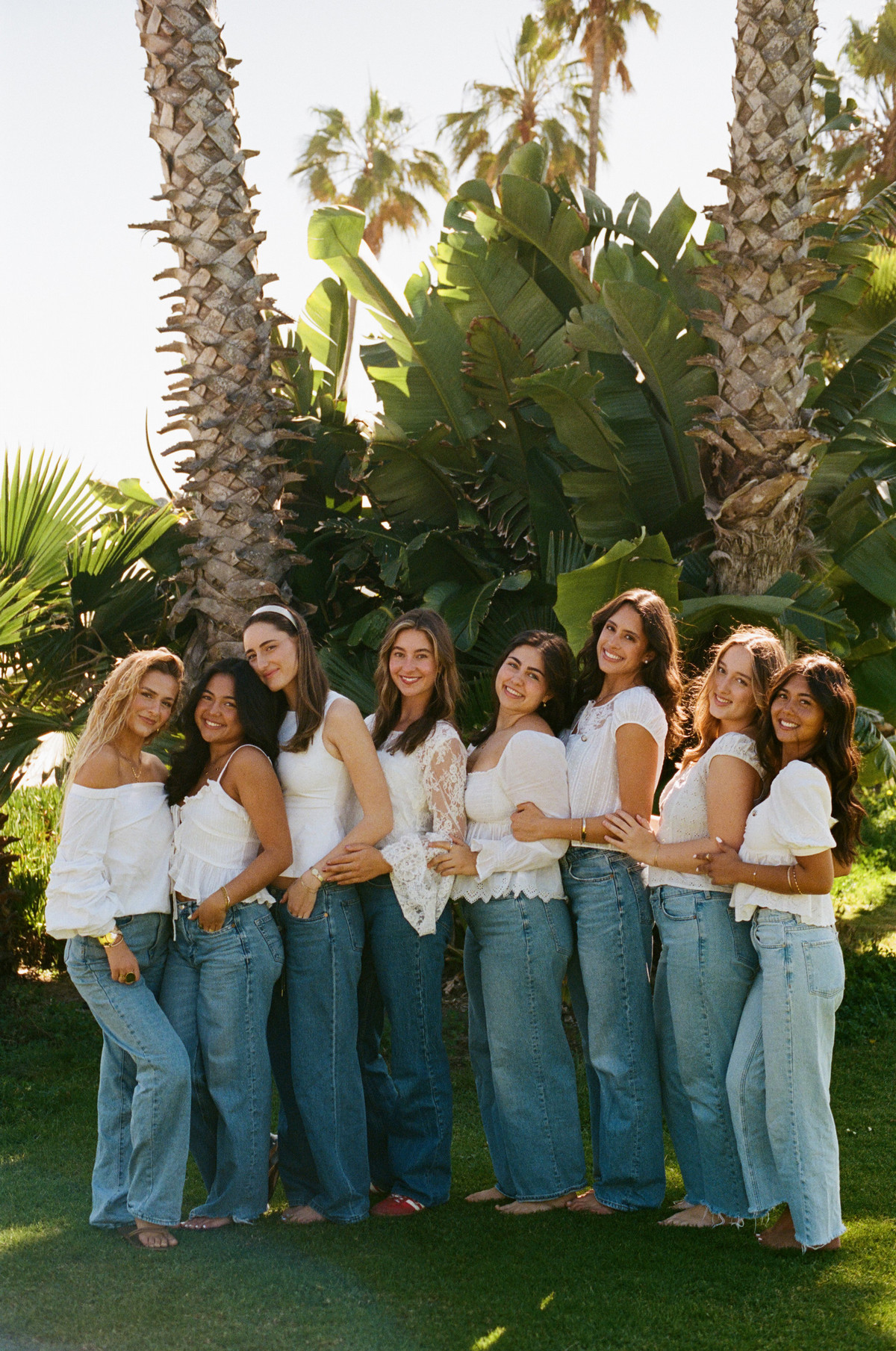 Women standing together in white shirts and blue jeans
