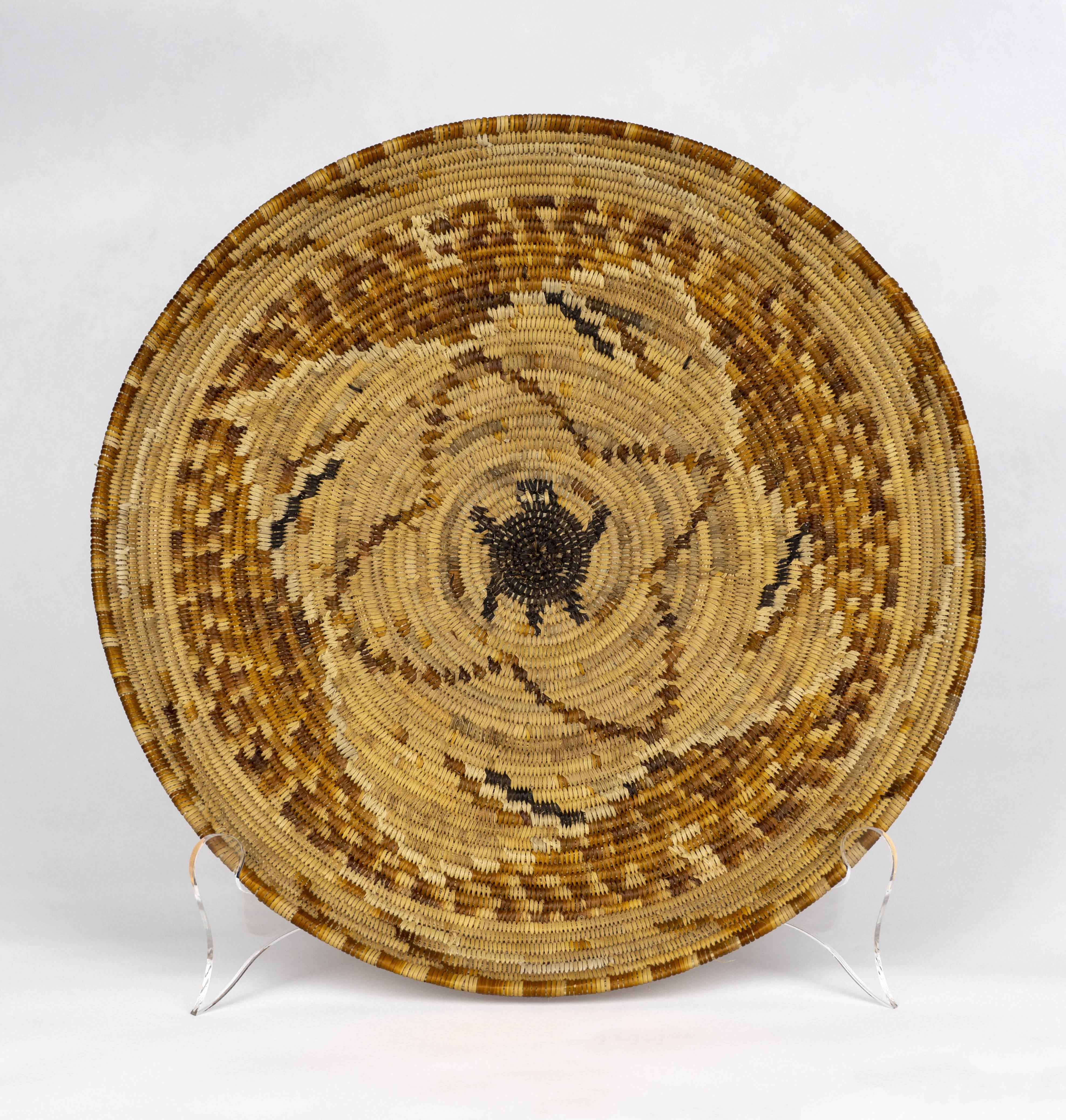 Traditionally woven flat basket with a turtle design at center
