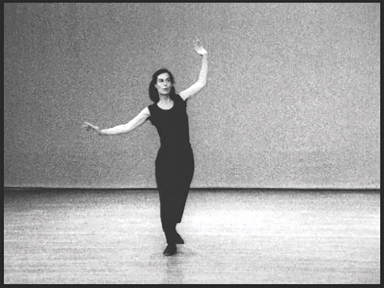 This is a black and white image of a woman, wearing all black, with her arms out at her side as if she was balancing.