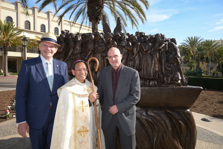 A photo of USD President Harris, Canadian artist Timothy Schmalz, and others standing outside near a new sculpture during a campus ceremony on Dec 18th.
