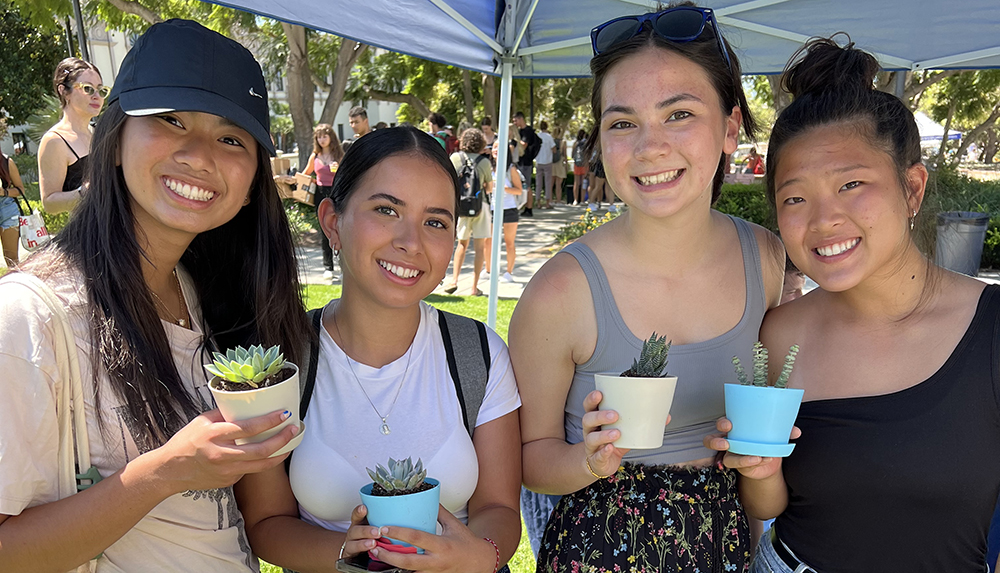 Image of four female students holding potted succulents
