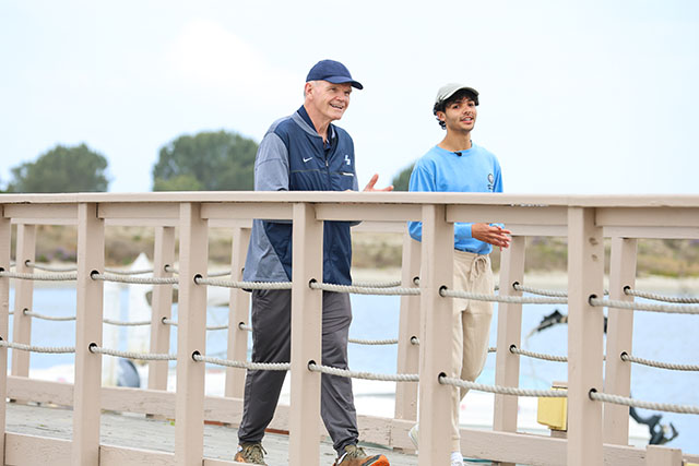USD President James T. Harris III, DEd; and 2025 President for a Day Cristian St. Clair stroll along a pier at Mission Bay. 