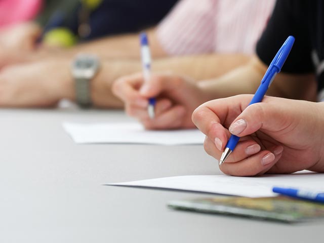 multiple pencils writing on paper as if a student were taking an exam