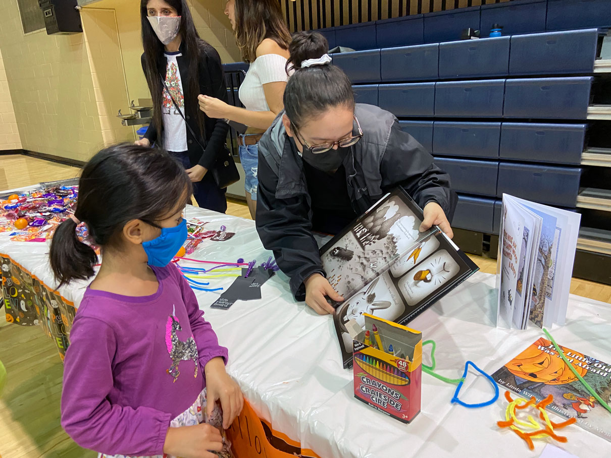 Mortar Board student reading to young student out of a children's book