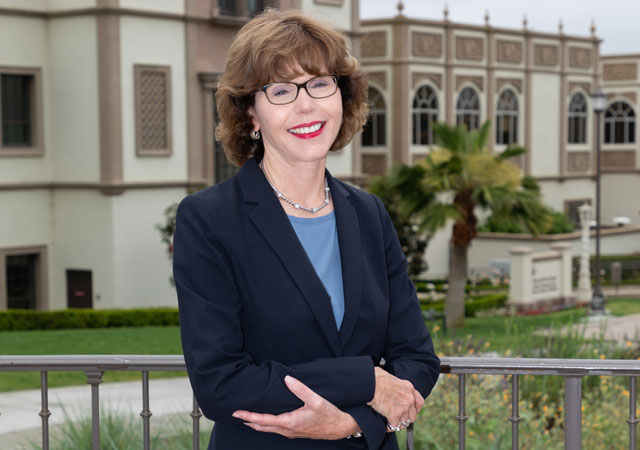 Laurie Ecoff standing in front of campus building