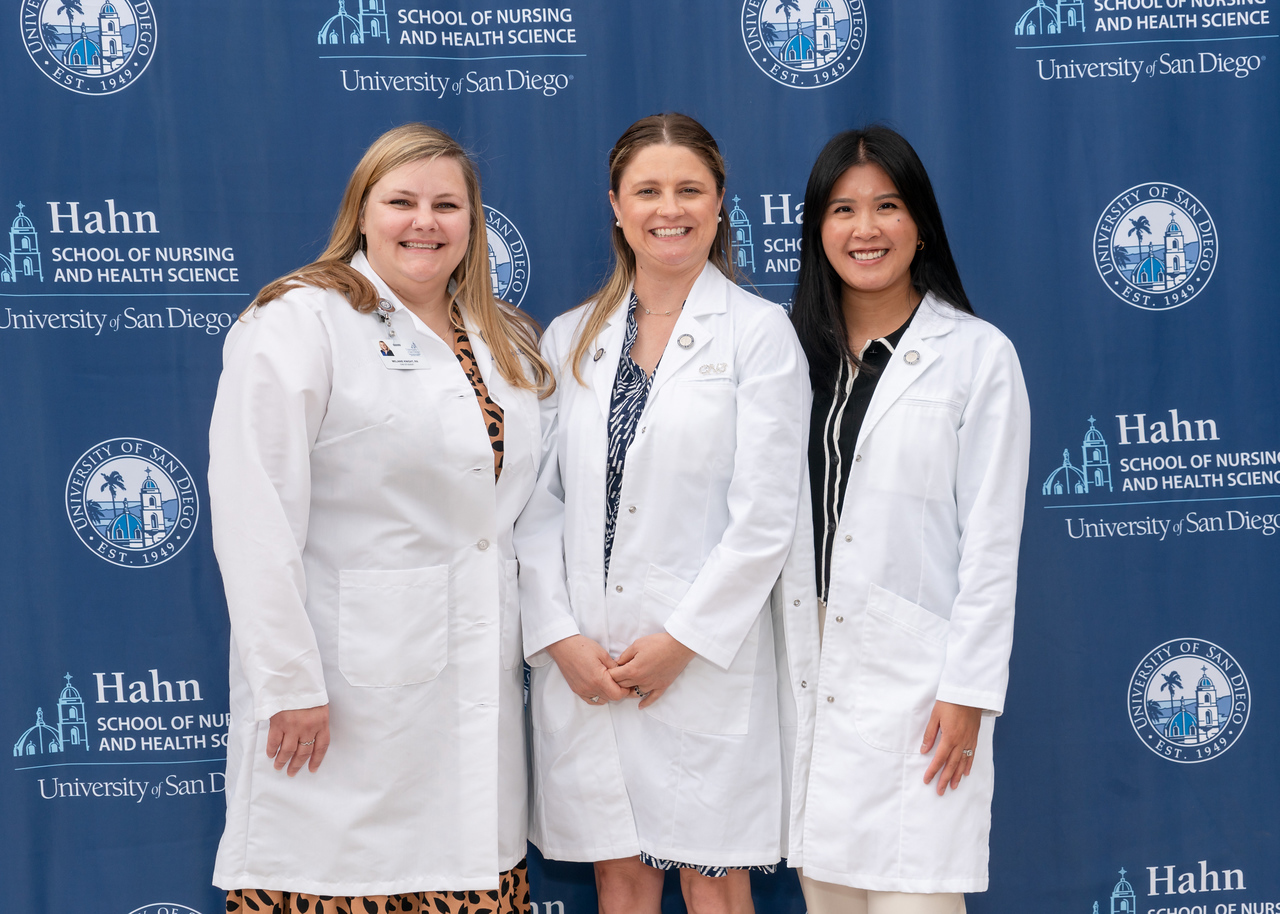 CNS graduates standing in front of USD blue logo backdrop