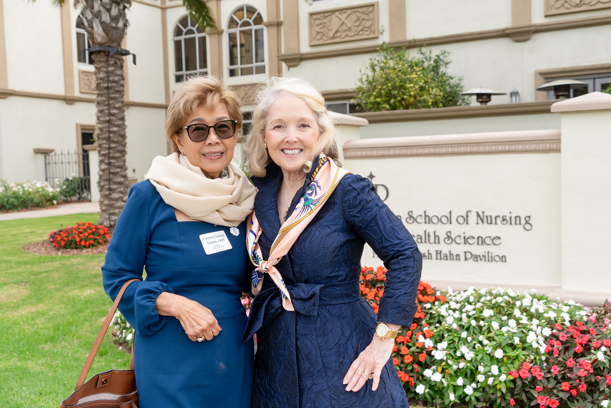 two nursing alumni in front of building