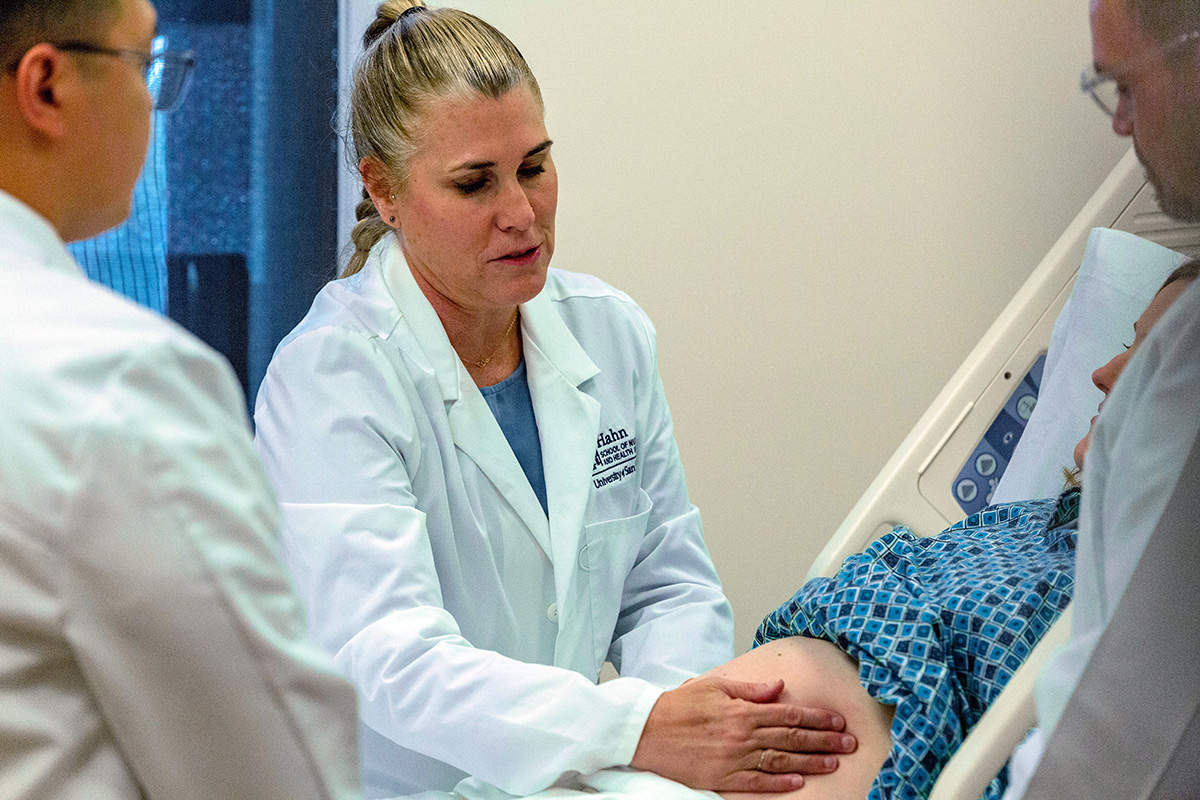 Advanced practice perinatal nurse practitioner performs a bedside examination of a pregnant patient during clinical care.