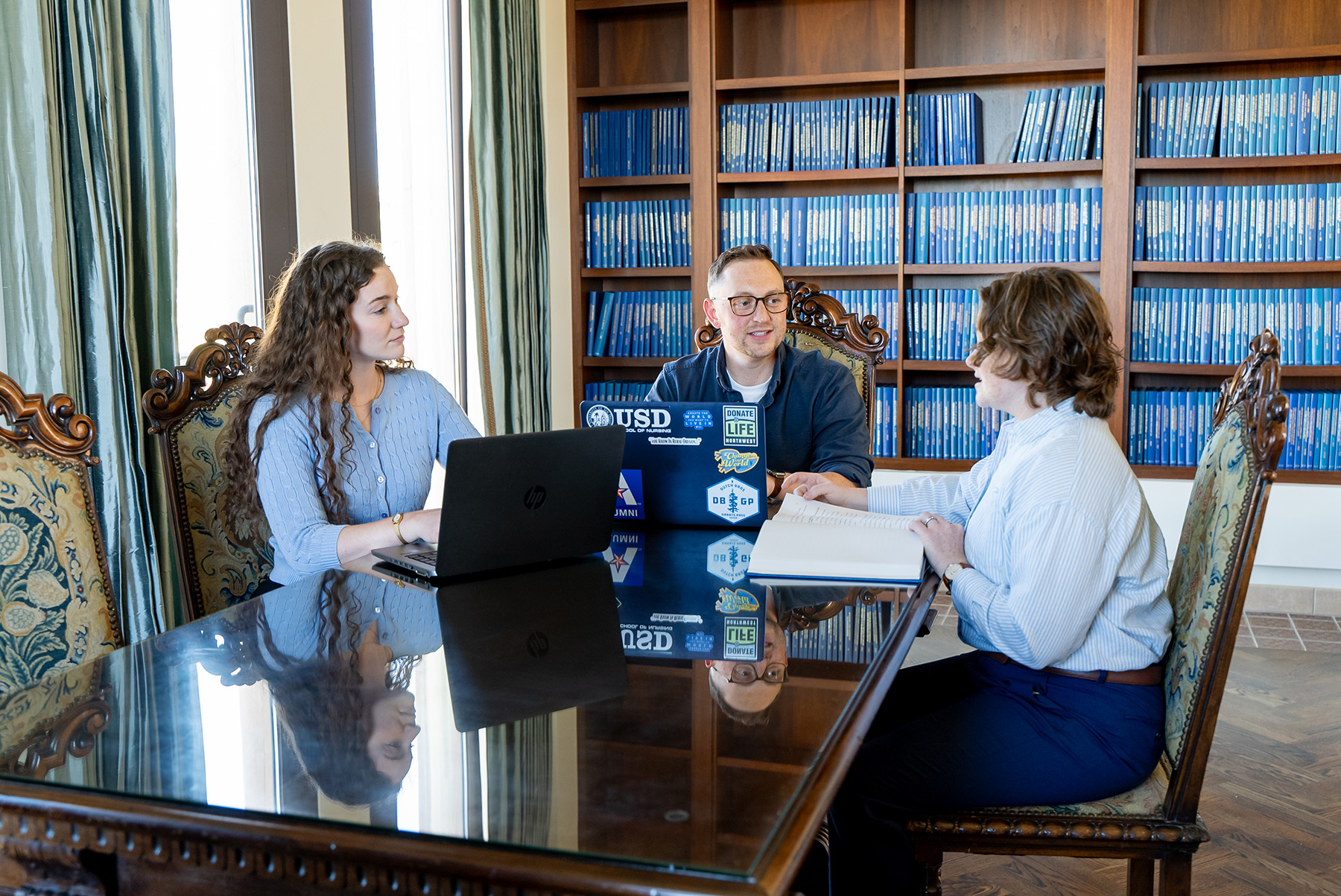 Three Nursing PhD students collaborating at a large table in the Krauss Family Graduate Study room, located within the Beyster Institute of Nursing Research.