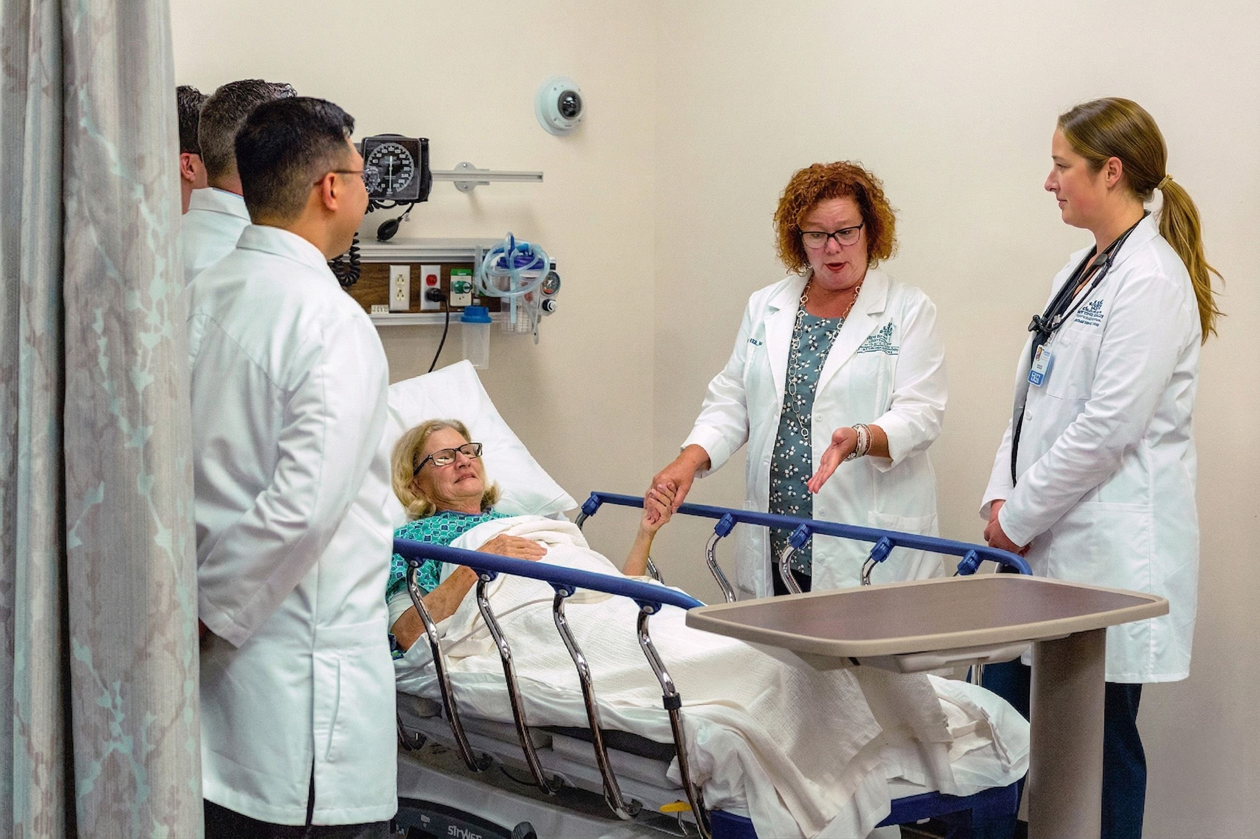 Group of CNS nursing students with faculty at patient's bedside