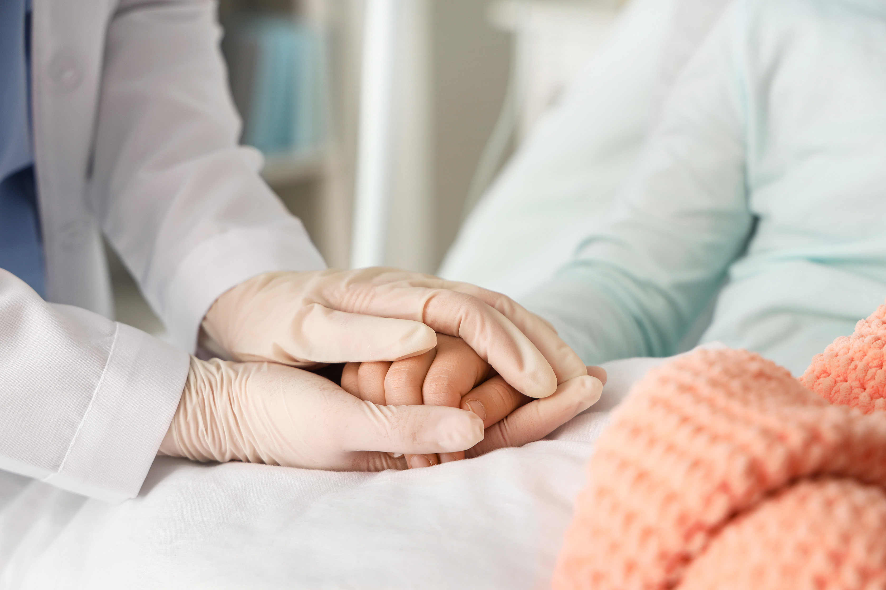 cns nurse holding hand of patient in hospital bed