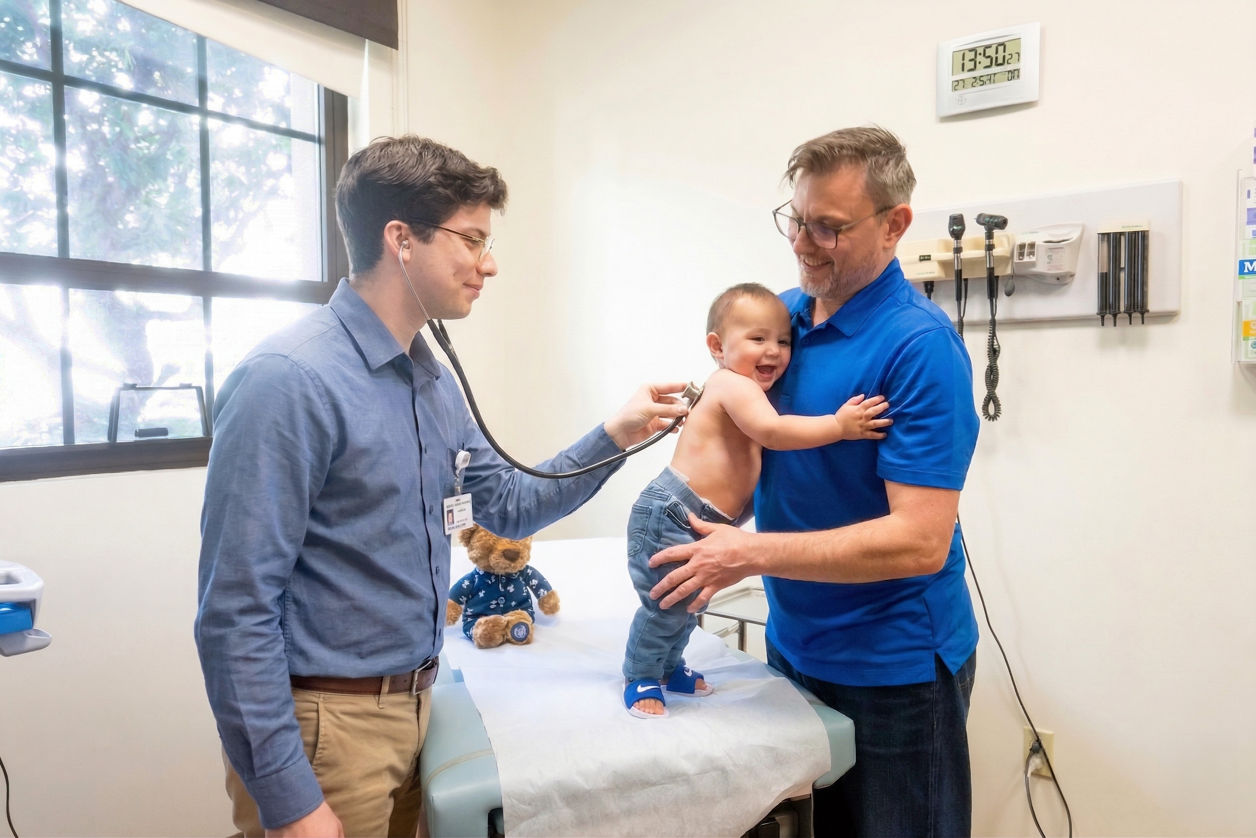 Peds NP student with baby and dad in sim lab exam room