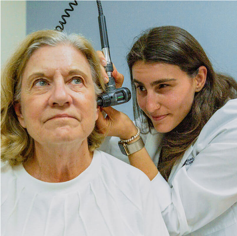 Nurse practitioner student examines patient in sim lab office setting