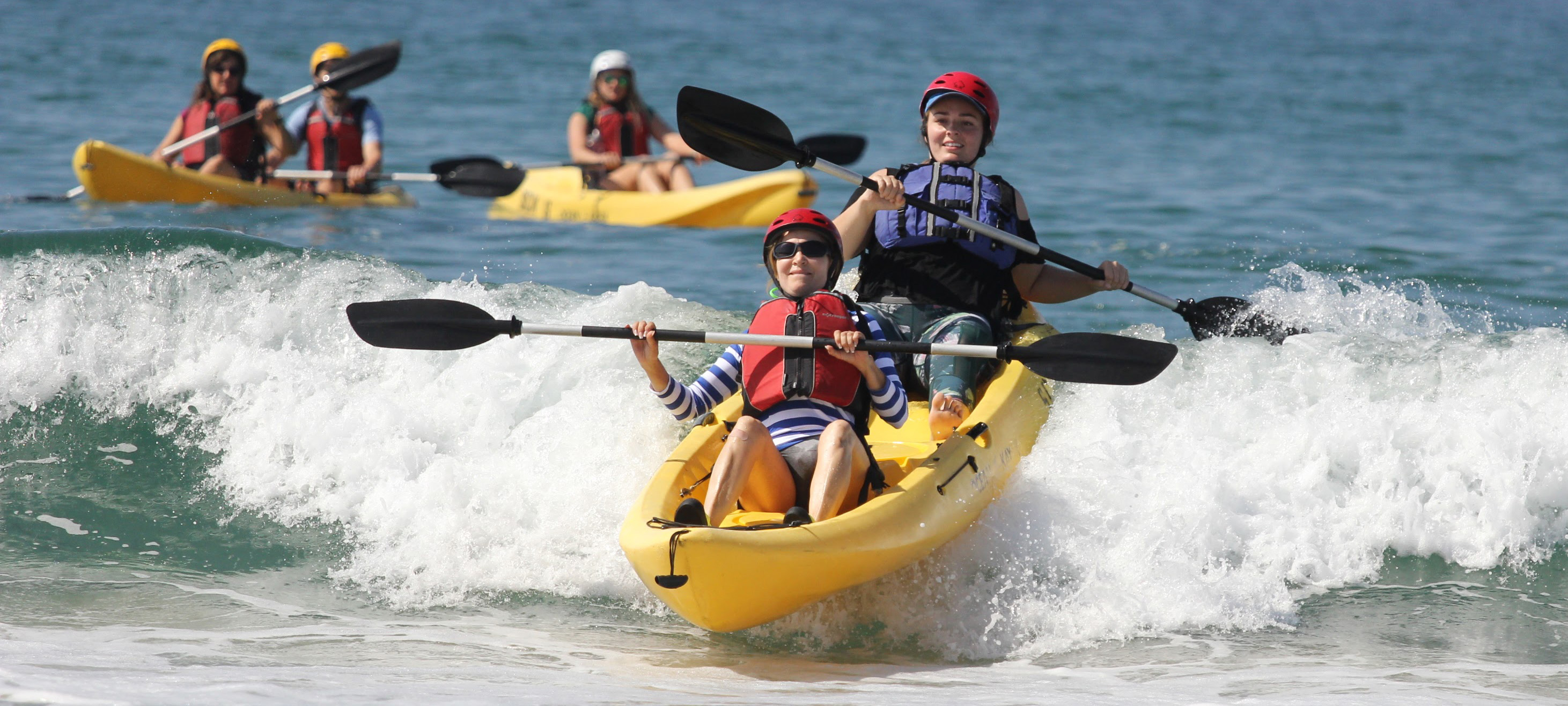 Students riding a wave on a kayak
