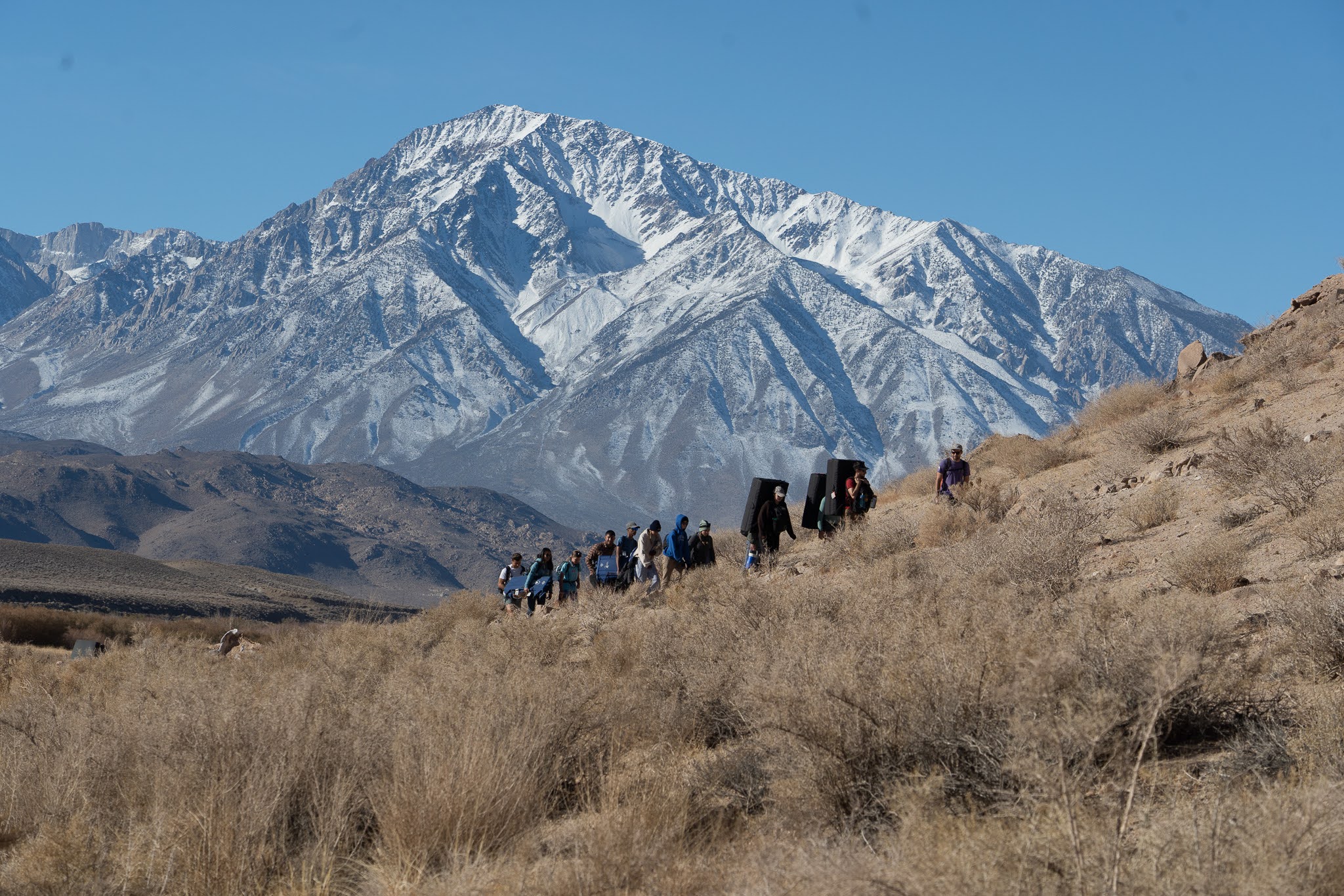 students hiking with a snow capped mountain in the background