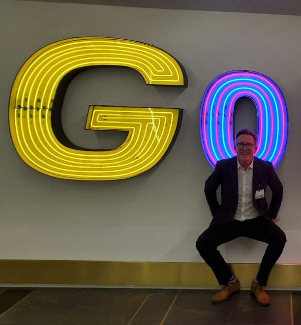 Dean Peacock in front of a neon sign